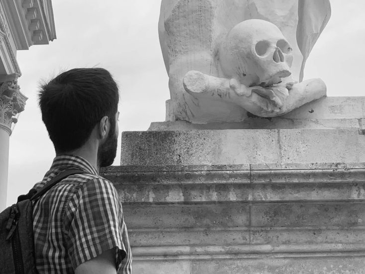 In this picture a student is looking at a skull. The student is faced with the reality that he has to grow old, to come of age, and that being too focused on “being an adult” at his young age makes him miss out on the pleasures of youth, these being the possibility to make the odd choice, go the longer road, take the unknown turn, to be unreasonable and make mistakes.
