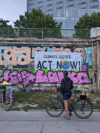 This picture portrays the political ideologies of European youth in several ways: in terms of self-expression, concern over the climate, and also political action.

The graffiti represents freedom of expression through art. The man facing the wall with his bike not only showcases the way of life of European youth but also his political and lifestyle choices. He stands alone, watching a world on fire, ready to fight for his ideals. There is a sense of helplessness and being on your own as the man stands alone, but the image also acts as a call for promoting actionable change.

Lastly, the picture shows how the world is a bizarre chaotic place (for example, looking at the sculptures on the bottom right), but the man is able to focus on the one thing that matters and gives him a sense of purpose.